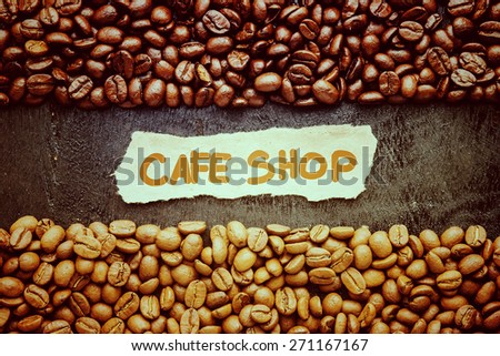 Coffee beans with Cafe Shop label on black wooden background. Photo in vintage color tone style.