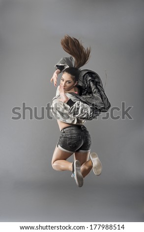 Urban dressed active girl jumps over grunge background