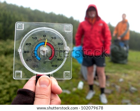 A temperature scale in a hand shows low temperatures in summer mountains