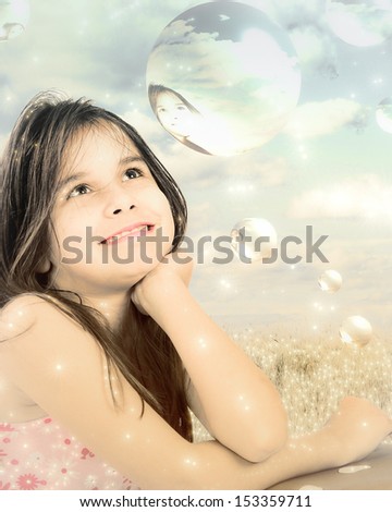 Fantasy photo of little girl dreaming surrounded by bubbles