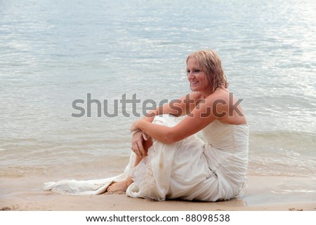 Bride sits on the beach during Trash the Dress