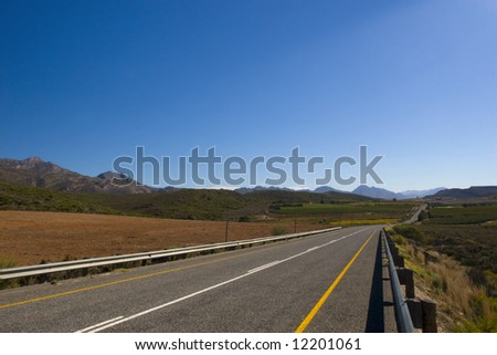A country road through the mountains on a clear day with blue sky