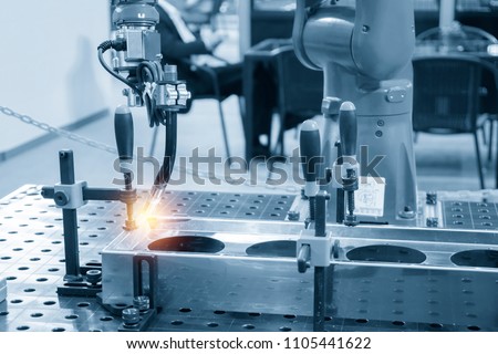 The welding robot machine for welding automotive part in the light blue scene.Industrial 4.0 concept for modern manufacturing process.