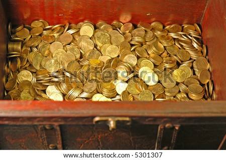 Reddish brown leather and wood treasure chest with gold colored coins (10 euro cent pieces) inside...Focus on the money inside