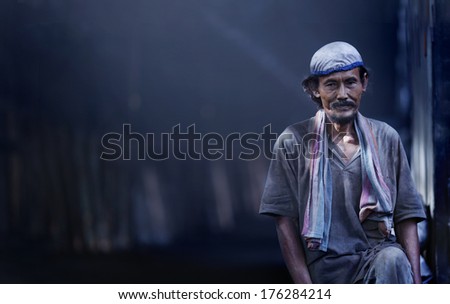 KUALA SEPETANG, MALAYSIA  - MAY 28: Unidentified workers in a charcoal factory standing alone waiting for his partner on  May 28, 2013 in Kuala Sepetang, Malaysia.