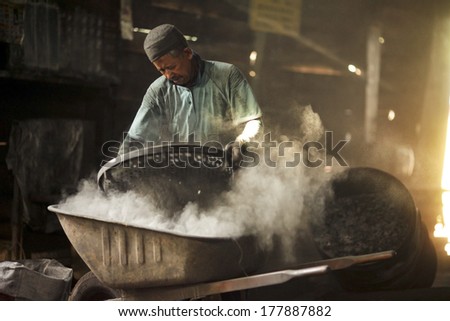 MALAYSIA, PERAK - JUNE 24 : Old man working in a dirty and dusty location at charcoal factory on JUNE 24, 2012 in Perak, Malaysia
