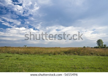 Farmhouse on the Kansas prairie under a cloud-streaked sky