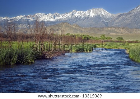 The Owens River flows against a background of snow-capped mountains.