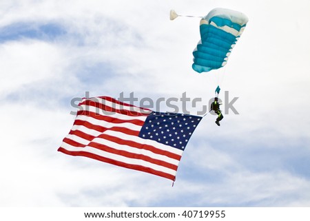 Sky diver carries an American Flag as he descends over an air show crowd in Thermal, California