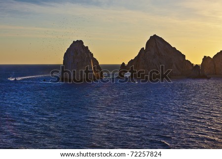 Boats skirt the famed hole in the rock at Cabo San Lucas, Mexico as the sun sets