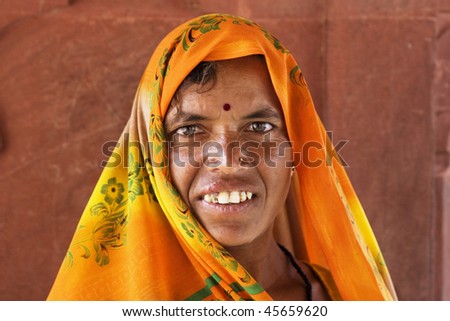 AGRA, INDIA - JUNE 18: An old Indian woman stands in front of the wall of temple on June 18, 2008 in Agra, India. Local women wear colorful saree (sari) as traditional clothing.