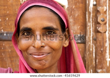 AGRA, INDIA - JUNE 18: Happy Indian woman stands in front of the wall of temple on June 18, 2008 in Agra, India. Local women wear colorful saree (sari) as traditional clothing.