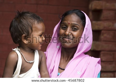 AGRA, INDIA - JUNE 18: Portrait of a happy Indian woman stands with baby in front of temple on June 18, 2008 in Agra, India. Local women wear colorful saree (sari) as traditional clothing.