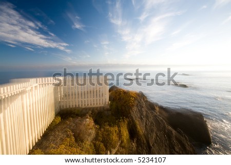 White picket fence overlook on cliff above ocean at sunset with dreamy zoom effect (3167)