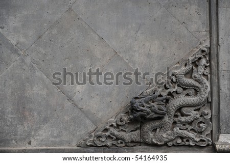 Decorative old sculpture of a dragon on a stone wall.