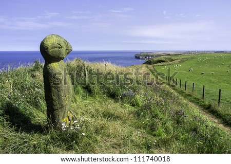 English coastline at Bempton, Yorkshire, UK A photograph of the walk path following the high cliffs of the English coastline at Bempton, Yorkshire. A wooden sculpture of a puffin in the foreground.