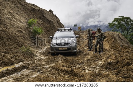 TAWANG, INDIA - SEP 19, 2011: Unidentified military personnel aid a car stuck in the deep mud along the main Assam highway on Sep 19, 2011 near Tawang, western Arunachal Pradesh, India.