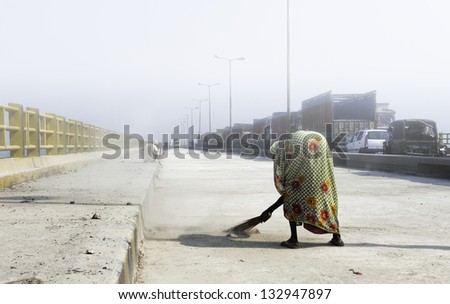 PATNA, INDIA - OCTOBER 14: unidentified woman in sari sweeps Mahatma Gandhi Bridge whilst under repairs on October 14, 2011 at Patna, Bihar, India.
