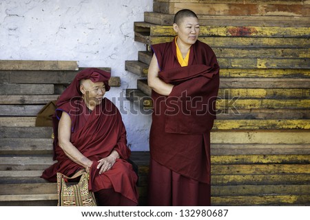 TAWANG, INDIA - SEPTEMBER 22: two Buddhist nuns in red robes rest before an important religious ceremony at 17th century Buddhist monastery on September 22, 2012 at Tawang, Arunachal Pradesh, India.