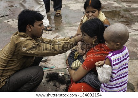 VARANASI, INDIA - OCTOBER 18: unidentified street barber shaves head of young boy accompanied by mother as part of rite of passage and initiation for Hindus on October 18, 2012 at Varanasi, India.