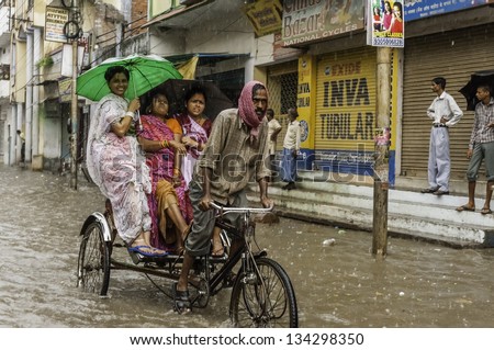 VARANASI, INDIA - AUGUST 11: Cycle rickshaw and passengers try to make headway through flood waters after monsoon storm in a busy street on August 11, 2011 in Varanasi, Uttar Pradesh, India.