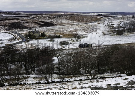 GOATHLAND, UK - MARCH 28: a vintage steam train makes the annual Easter run through the snow covered landscape of the North York Moors on March 28, 2013 near Goathland, Yorkshire, UK.