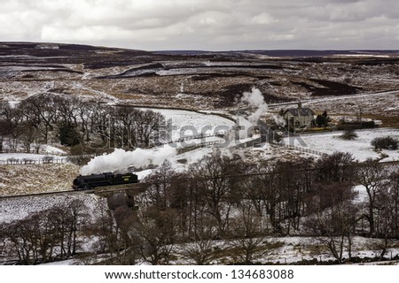 GOATHLAND, UK - MARCH 28: a vintage steam train makes the annual Easter run through the snow covered landscape of the North York Moors on March 28, 2013 near Goathland, Yorkshire, UK.