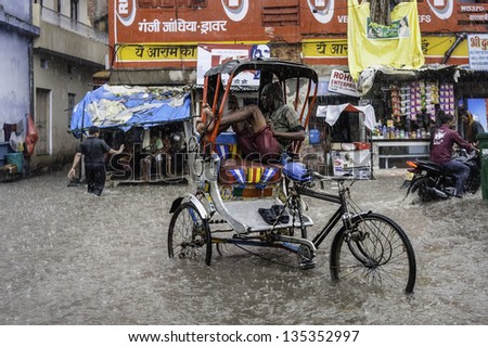 VARANASI, INDIA - AUGUST 11: monsoon rain and flash flood yet a man and his cycle rickshaw is still plying for business on August 11, 2011 in Varanasi, India.