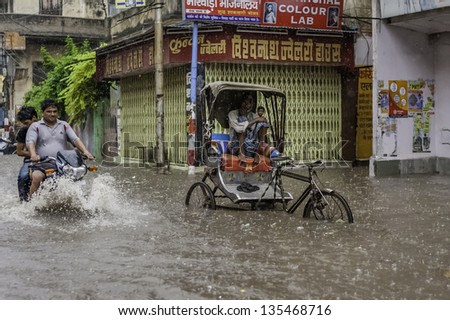VARANASI, INDIA - AUGUST 11: Heavy monsoon rain causes a flash flood yet people including a man with his cycle rickshaw continue with business as usual on August 11, 2011 in Varanasi, India.