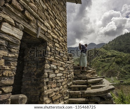 TAWANG, INDIA - SEPTEMBER 15: unidentified woman separates home grown soya bean from the chaff  next to a traditional stone house on September 15, 2011 in Dirang, Tawang, Arunachal Pradesh. India.