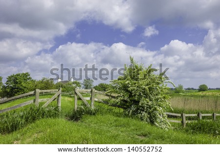 Hull, England, UK. A fence and a footpath with hawthorn in bloom along the bank of the river Hull on a bright spring day near Kingswood.