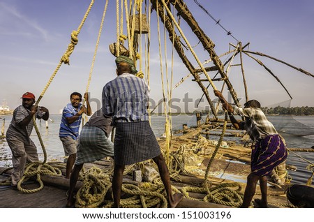 FORT KOCHI, INDIA - JANUARY 07, 2011: Local fishermen pull on ropes to lift a large Chinese fishing net out of the sea on January 07, 2011 at Fort Kochi harbour, Kerala, India.