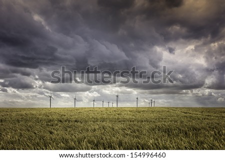 Beverley, Yorkshire, UK: Wind farm (turbines) in a field of wheat ready for harvesting. A storm is brewing in this village farmland near Beverley, Yorkshire, UK.