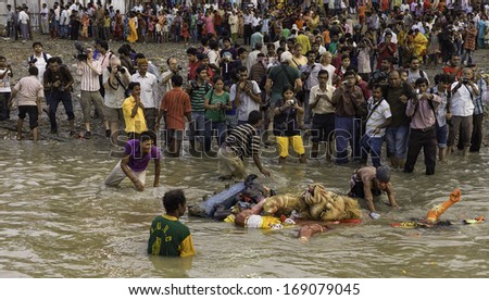 KOLKATA, INDIA - OCTOBER 07: Effigies of Hindu Gods are returned to Hoogly river to mark end of Durga Puja festival as spectators  and photographers observe on October 07, 2011 in Kolkata, India.
