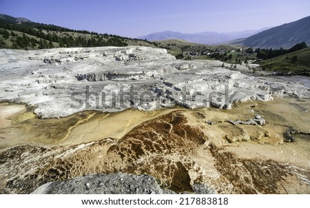 Mammoth, Wyoming, USA - Calcium Carbonate deposits from hot springs in the heart of Yellowstone National Park with the town of Mammoth in the background, Wyoming, USA.