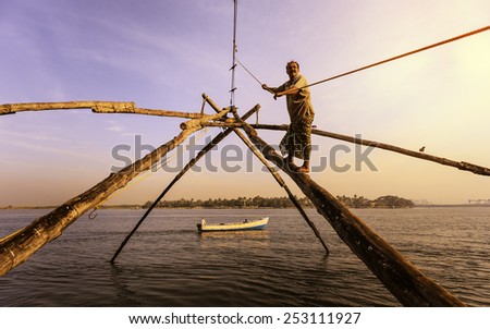 FORT KOCHI, INDIA - JANUARY 01, 2012:  Fisherman walks up wooden beam of Chinese fishing net to act as cantilever weight at sunset in harbour on January 01, 2012 in Fort Kochi, Kerala, India.