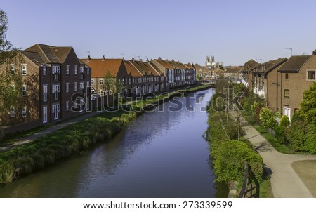 Beverley, Yorkshire, UK. View along the beck (canal) flanked by residential houses with the minster (church) on the horizon, Beverley, Yorkshire, UK.