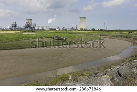 Paull, Holderness, Yorkshire, UK. Hedon Haven at low tide, and the large chemical plant in the background with a rotting wooden boat on the mud bank near Paul, East Riding of Yorkshire, UK.