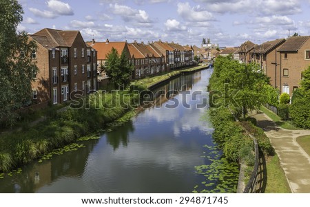 Beverley, Yorkshire, UK. The beck (canal) on a bright summer day with a view of town houses, the canal banks and footpath, and on the horizon, Beverley Minster, East Riding of Yorkshire, UK.