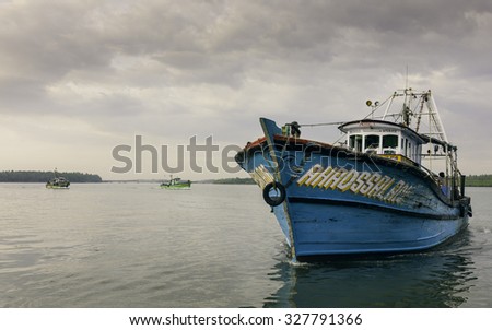 KANNUR, INDIA - DECEMBER 30, 2011: Trawlers return at dusk from deep sea fishing trip in Arabian Sea and anchor at Valapattam harbour on December 30, 2011 near Kannur, Kerala, India.