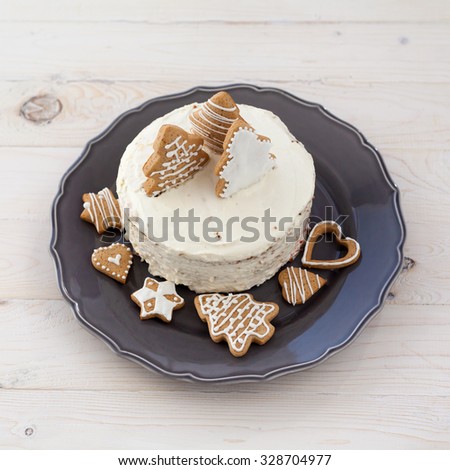 White cake with cookies in the shape of Christmas trees on a wooden white background
