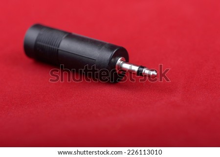 A headphone jack plug adapter on a red background