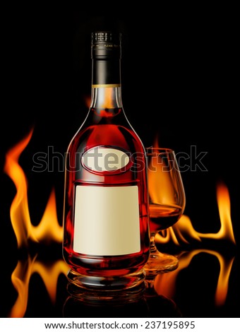 Cognac bottle and a glass in front of fireplace
