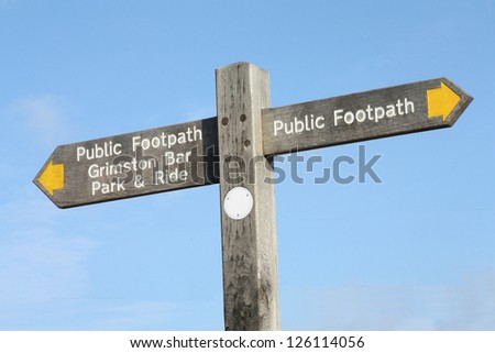 Public footpath sign against a blue sky.