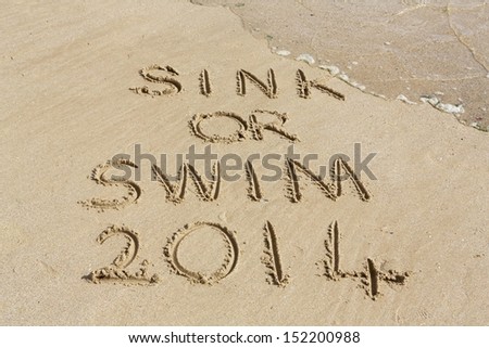 \'Sink or swim\' written on a sandy beach partly obscured by a wave.
