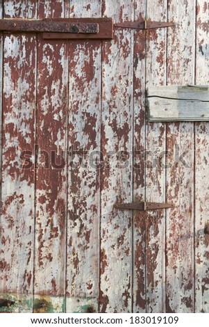 Dark red paint peeling from an old wooden door.