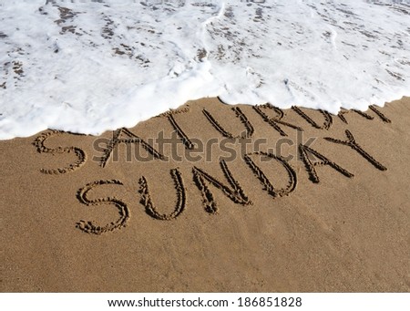 Sunday is coming concept - inscription Saturday and Sunday written on a sandy beach, the wave is starting to cover the word Saturday.