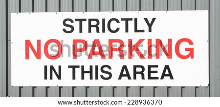 Strictly No Parking sign written on a metal wall.
