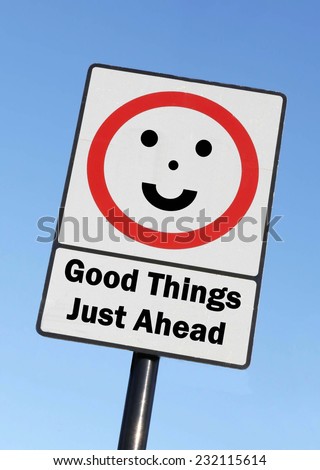 Good Things Just Ahead written on a road sign with a smiling face against a clear blue sky background