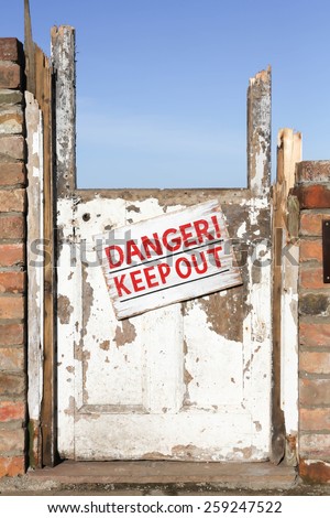 Old wrecked door with 'Danger Keep Out' warning sign